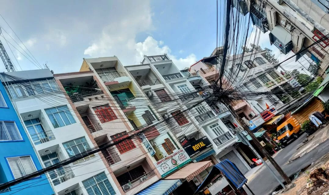 Strands of electrical and fiber optic cable, some as thick as an arm, connect buildings and distribution boxes on a side street in District 1, Sài Gòn. Because of their low cost and the constant risk of flooding during the rainy season, cables are most often laid above ground, except in large construction projects. Every electrician's nightmare.