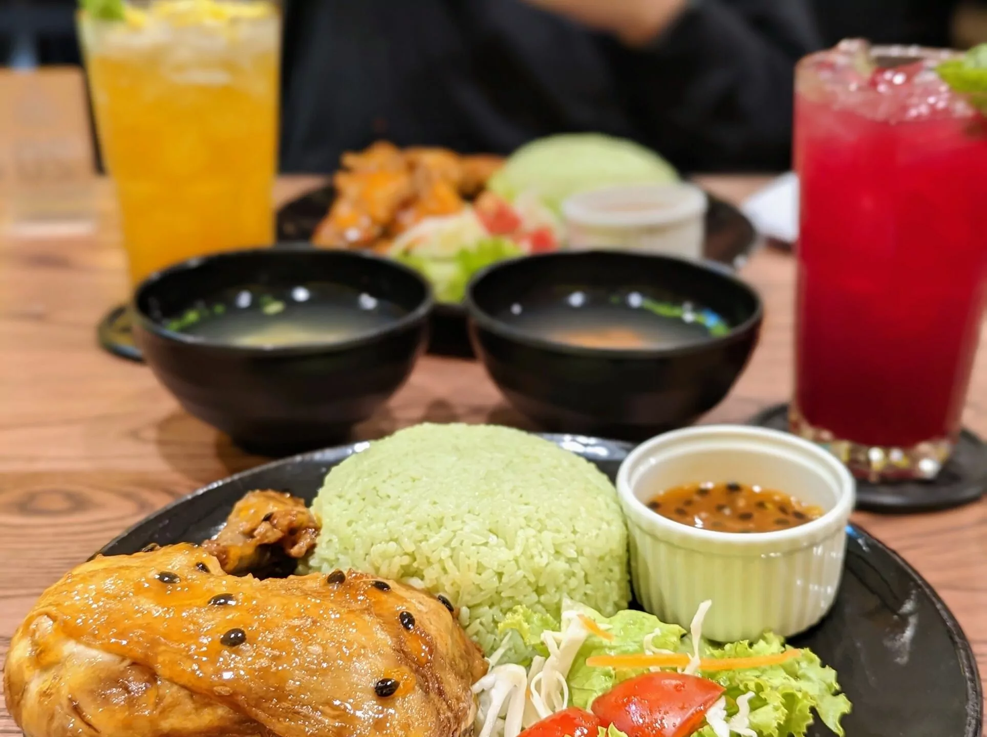 Cơm gà sốt chanh dây, crusty grilled chicken leg with sweet and sour passion fruit sauce, served with steamed tender green rice, salad, and a glass of freshly squeezed mango juice. Always according to the motto: A chicken a day keeps the doctor away. Price: 81,000 VNĐ (≈3.22 EUR).
