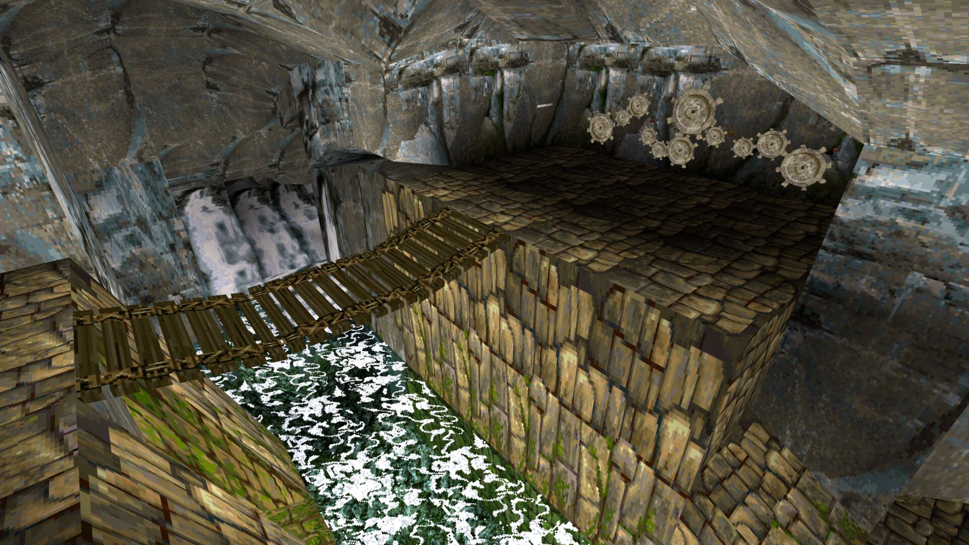 This screenshot shows a bridge over a river leading to a gear riddle on a cave wall from Tomb Raider 1 Remastered. It features the original 1996 graphics.
